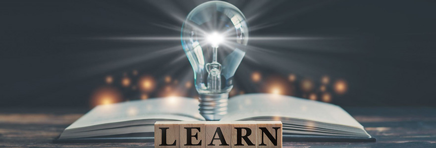 A light bulb standing on top of an open book with the word "learn" in front of it
